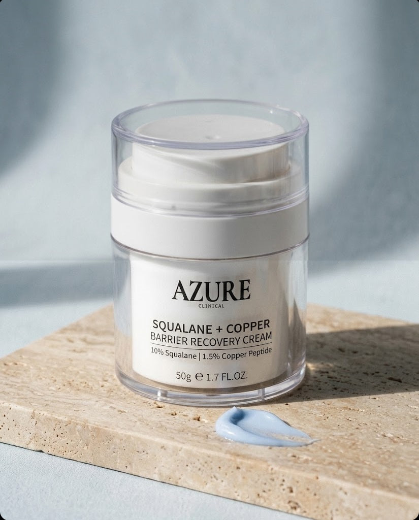 Azure Clinical Squalane + Copper Barrier Recovery Cream airless pump jar on travertine stone with a swirl of powder-blue cream